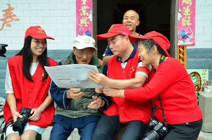 志愿者正在给百岁老人读《潼南日报》。
