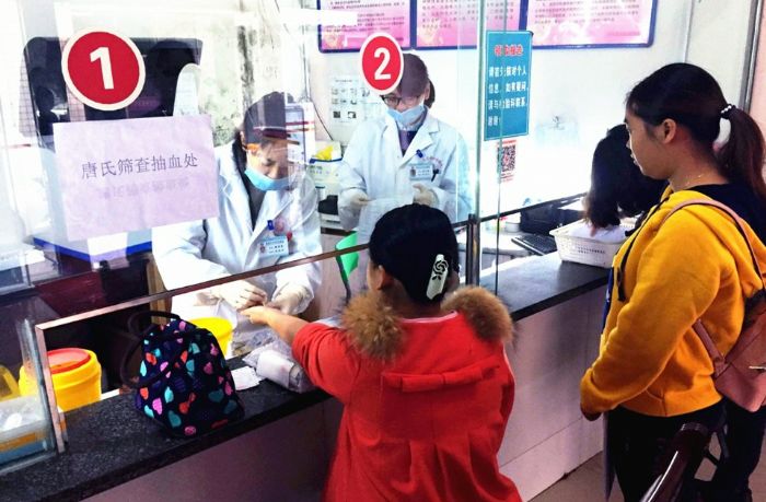 一位准妈妈正在医务人员帮助下进行唐筛抽血。
