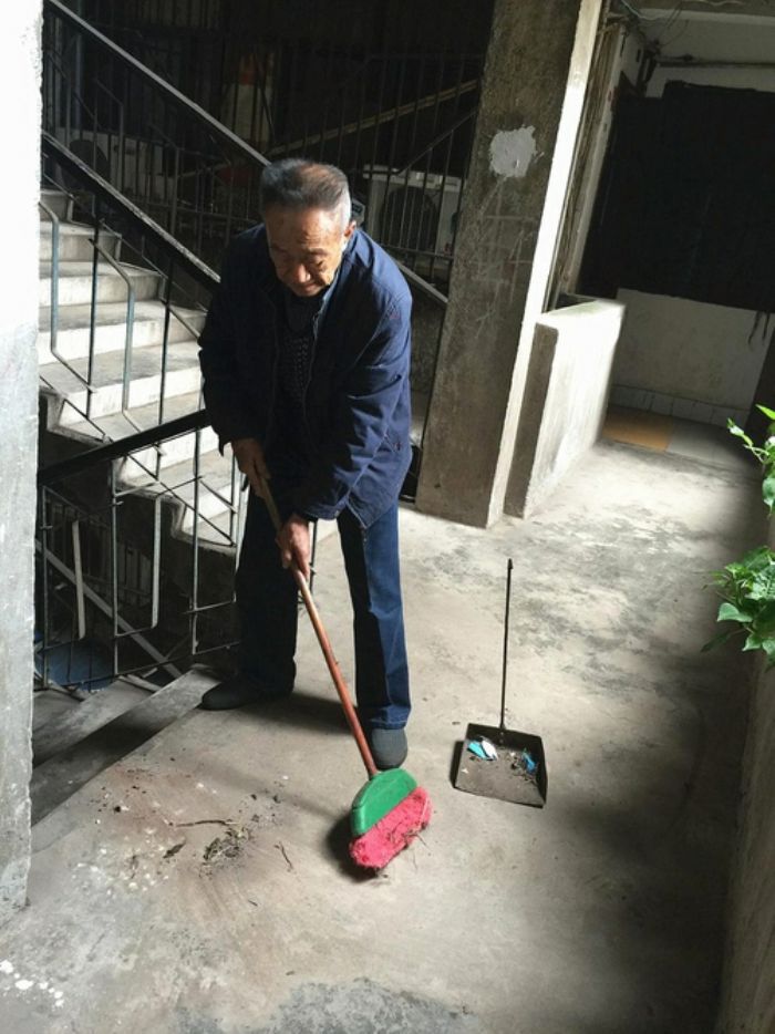 曾智根在打扫小区楼道卫生。
