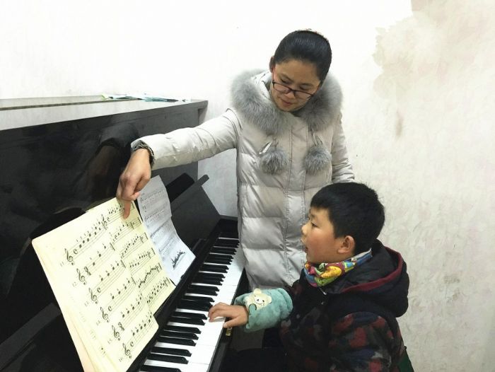 家长陪孩子学习钢琴。
