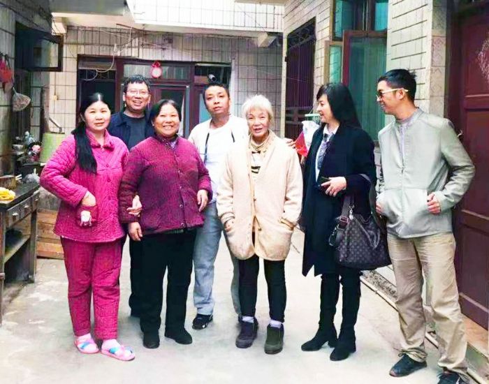 周昌平老人（前排中）一家团聚后与救助人员合影。

