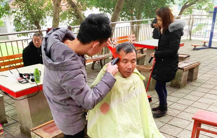 志愿者为老大爷理发。全媒体记者米莲摄
