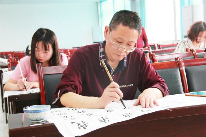 参赛选手正专心致志写毛笔字。
