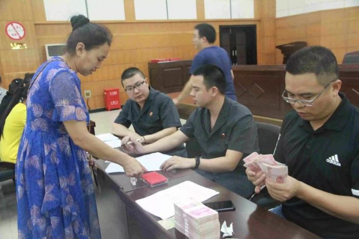 工作人员为农民工发放执行款。

