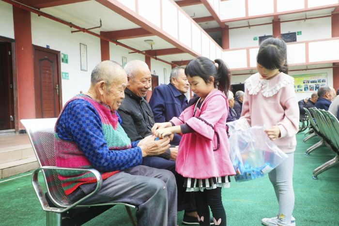 爱心企业员工家的小孩为老人送上礼物
