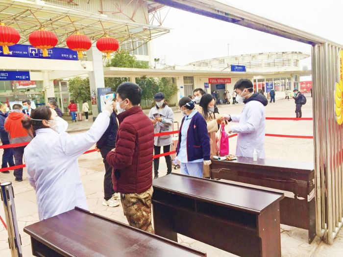 医务人员在火车站检测点对乘客进行体温监测
