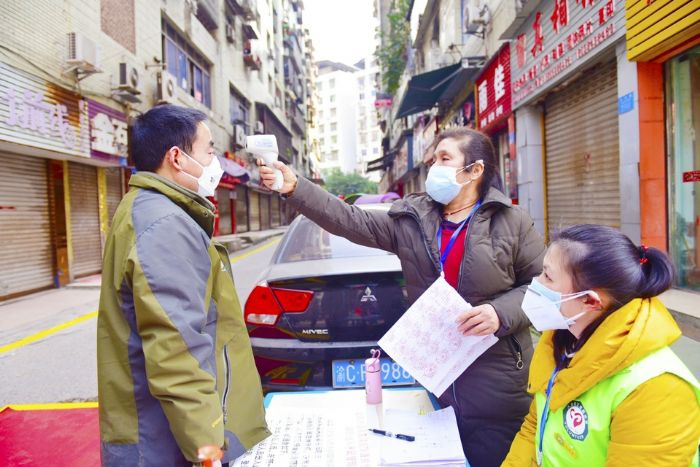 社区工作人员为进出居民测量体温。
