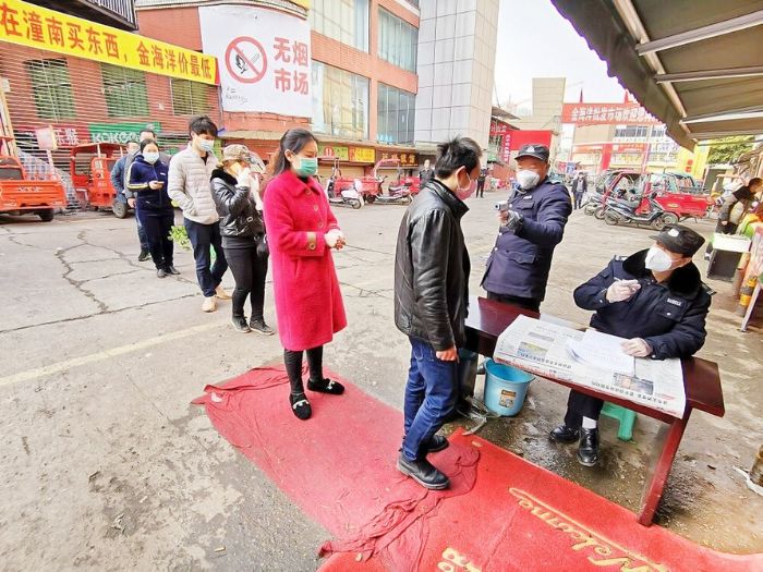 前来买菜的市民有序等待测量体温
