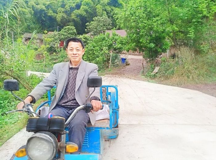 贫困户匡世洪在新建道路上运送农资到场镇销售
