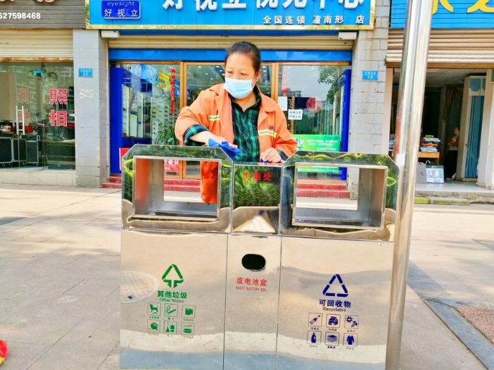环卫工人在清洁垃圾箱。
