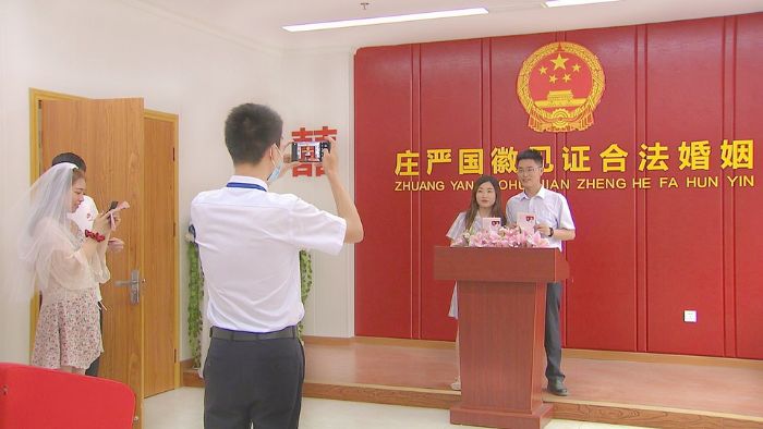 一对新人在庄严的国徽下合影留念

