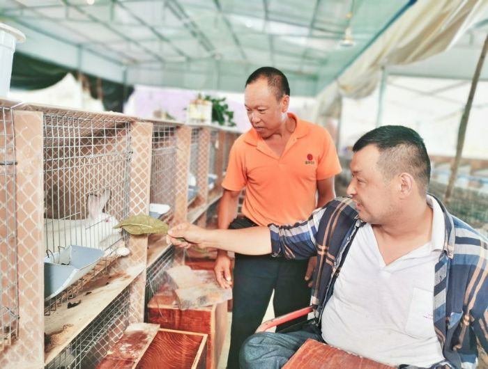致富带头人米泽建（右一）向贫困户传授养兔经验。
