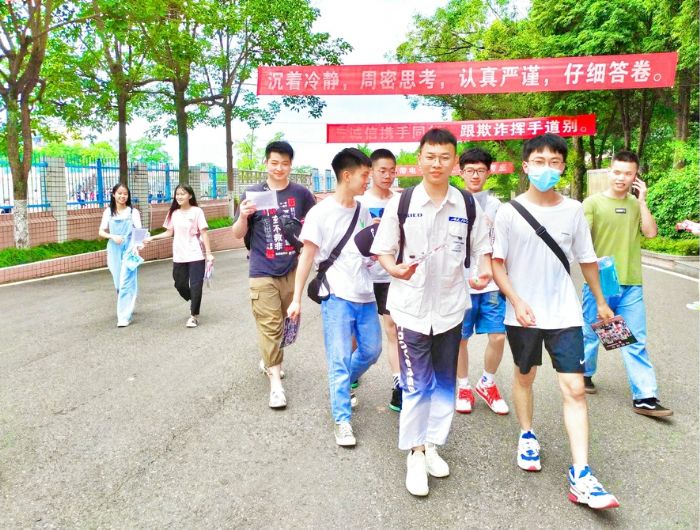 考试结束，同学拿着毕业照走出学校。
