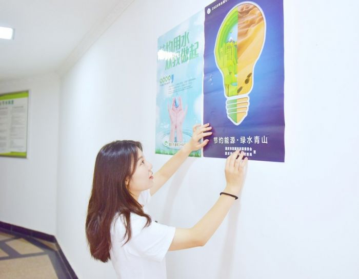 　　区机关事务管理中心工作人员在醒目位置张贴节约宣传海报。

