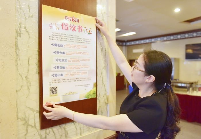 ▲区机关食堂工作人员张贴倡议书，倡导大家吃得干净、吃得合理。