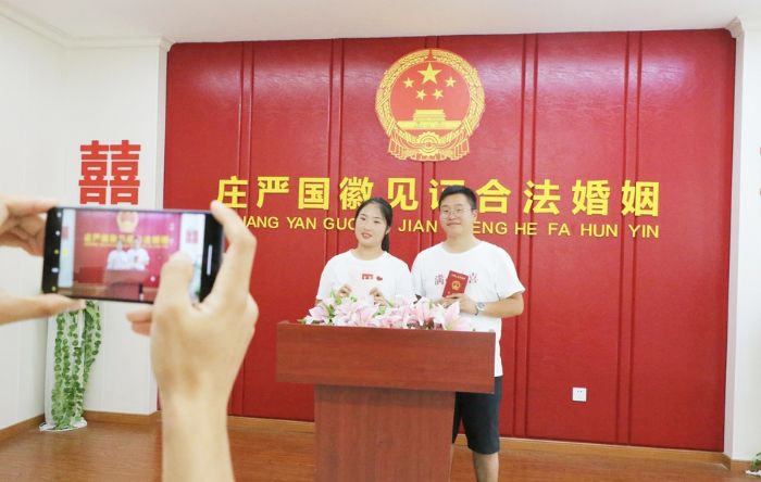 一对新人在庄严的国徽下拍照留念。
