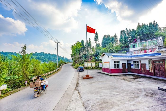 摩托车在安装了防护栏的农村公路上行驶。
