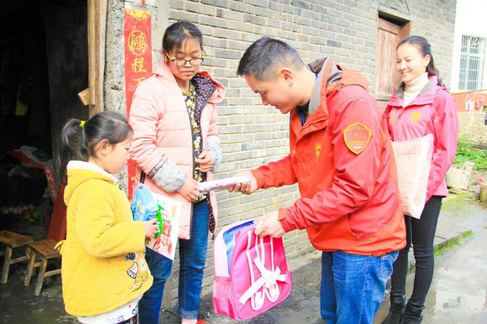 志愿者为贫困学生送学习用品。
