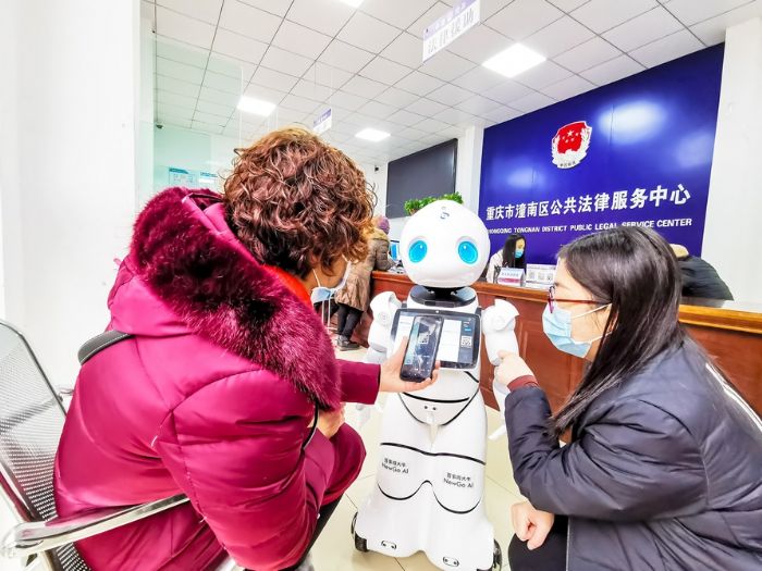 市民在工作人员的指导下用智能法律机器人查询资料。
