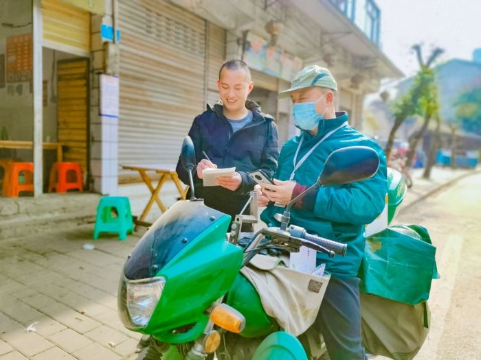 投递员穿梭在乡间小路，为群众收寄快递。
