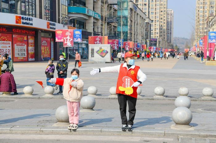 “红领巾志愿者”在家长的带领下指挥交通。
