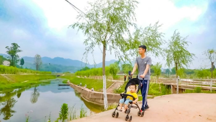 家长带着孩子在滨江路散步。
