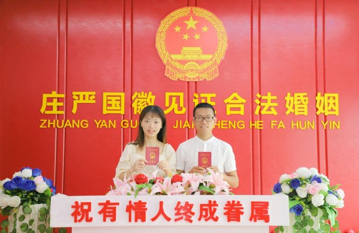 一对新人在庄严的国徽下合影留念。全媒体记者陈晓芳摄
