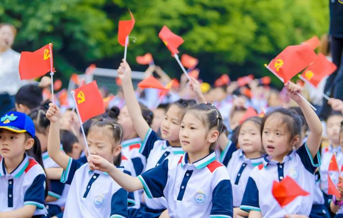区人民小学学生挥舞红旗为演出加油。
