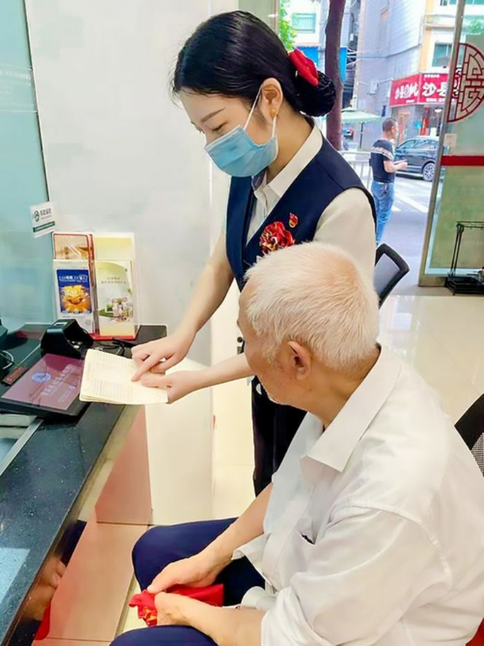 农商行工作人员悉心为老年人讲解存款取款注意事项。
