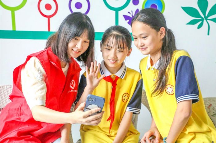 学生在老师陪同下通过手机与父母视频聊天。
