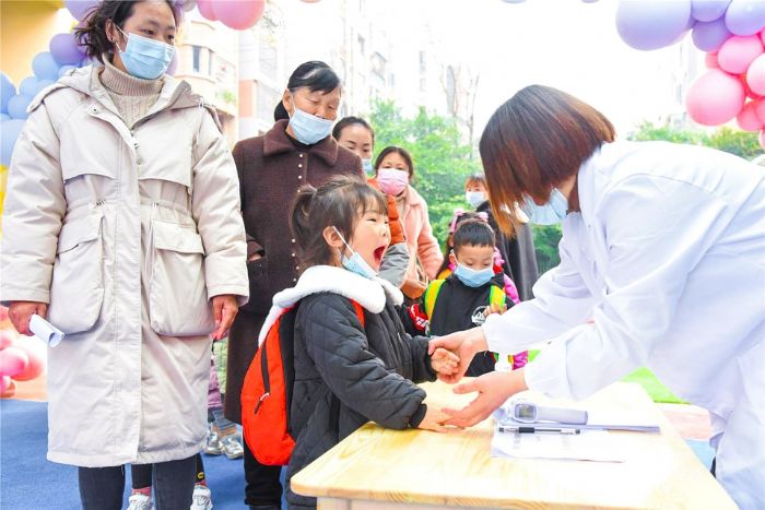 老师对入园学生进行防疫和健康检查。
