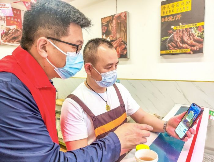 高梯社区干部在指导商户下载、张贴场所码。

