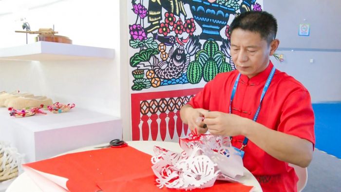 潼南非遗文化传承人张建在现场展示剪纸技艺。
